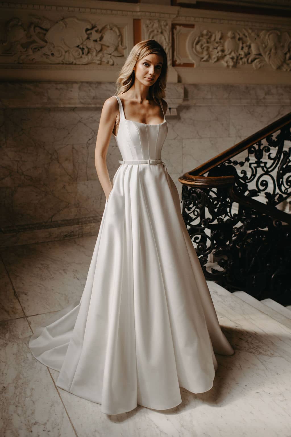 Beautiful Suzanne Neville Bussotti has a soft square neckline with slight scoop, seaming detail on the corseted bodice, delicate straps and a pleated full A-line skirt. Find your wedding dress at Your Dream Bridal in Sudbury MA.